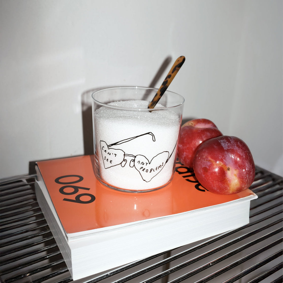 Wasserglas mit Schriftzug Cant see any problems. Das Glas steht auf einem Buch, zwei Äpfel liegen dahinter. Das Glas ist mit Zucker befüllt.