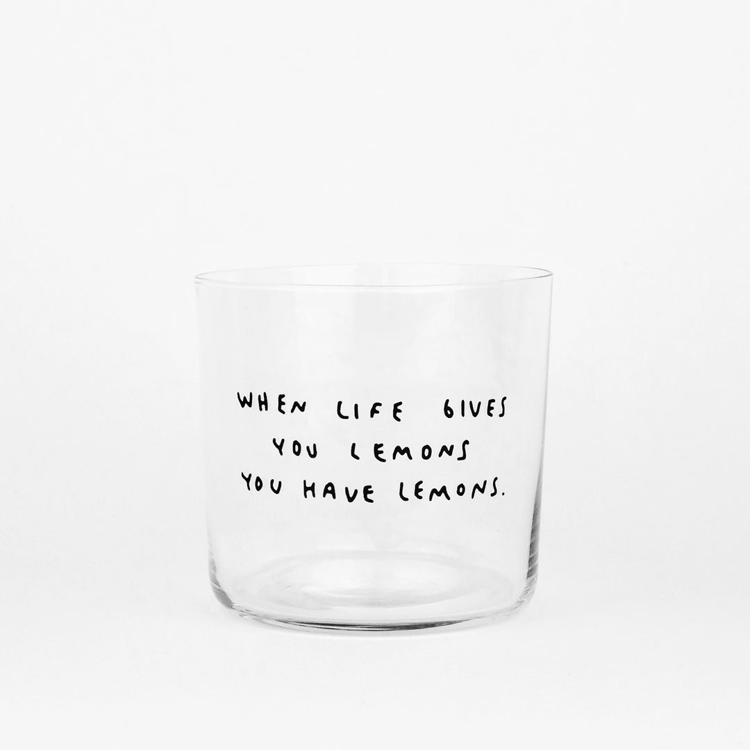 Designer Glas - Mittelgroß - mit schwarzem Spruch "When life gives you lemons you have lemons" auf der Front. Weißer Hintergrund,