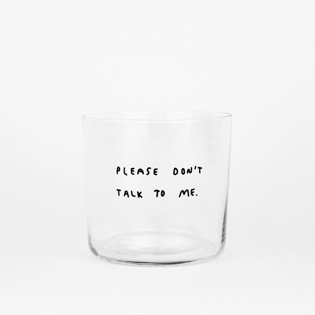 Transparentes Designer Glass mit schwarzem Schriftzug "Please dont talk to me". Weißer Hintergrund.