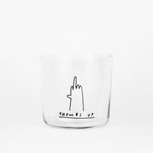 Medium Designer-Trinkglas mit sehr dünnen Glaswänden und einer schwarzen, einfarbigen Illustration auf der Vorderseite. Das Motiv zeigt eine Typografie in der geschrieben THUMBS UP und einer Illustration einer Hand die den Mittelfinger zeigt auf weißem Hintergrund.