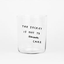 Großes Designer-Trinkglas mit sehr dünnen Glaswänden und einer schwarzen, einfarbigen Illustration auf der Vorderseite. Das Motiv auf dem Glas ist eine Handschrift in Schwarz in der geschrieben ist The secret is not to think wobei das think durchgestrichen ist und drunter das Wort CARE steht, auf weißem Hintergrund.