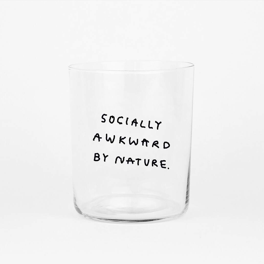 Großes Designer-Trinkglas mit sehr dünnen Glaswänden und einer schwarzen, einfarbigen Illustration auf der Vorderseite. Das Motiv auf dem Glas ist eine Handschrift in Schwarz in der geschrieben ist SOCIALLY AWKWARD BY NATURE auf weißem Hintergrund.