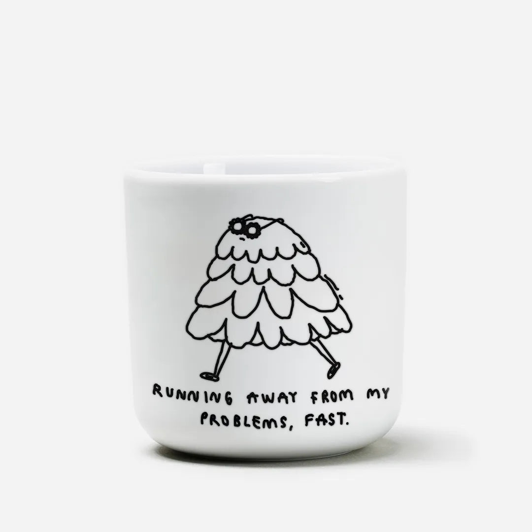Weißer henkelloser Porzellan-Becher mit einer einfachen schwarzen Illustration einer kleinen, flauschigen, cartoonartigen Figur mit Beinen, die davonläuft. Unter der Zeichnung steht in handschriftlicher Schrift der Satz: „Running away from my problems, fast.“ (Deutsch: „Ich renne schnell vor meinen Problemen davon.“).