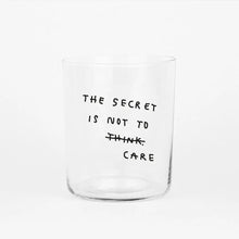 Großes Designer-Trinkglas mit sehr dünnen Glaswänden und einer schwarzen, einfarbigen Illustration auf der Vorderseite. Das Motiv auf dem Glas ist eine Handschrift in Schwarz in der geschrieben ist The secret is not to think wobei das think durchgestrichen ist und drunter das Wort CARE steht, auf weißem Hintergrund.