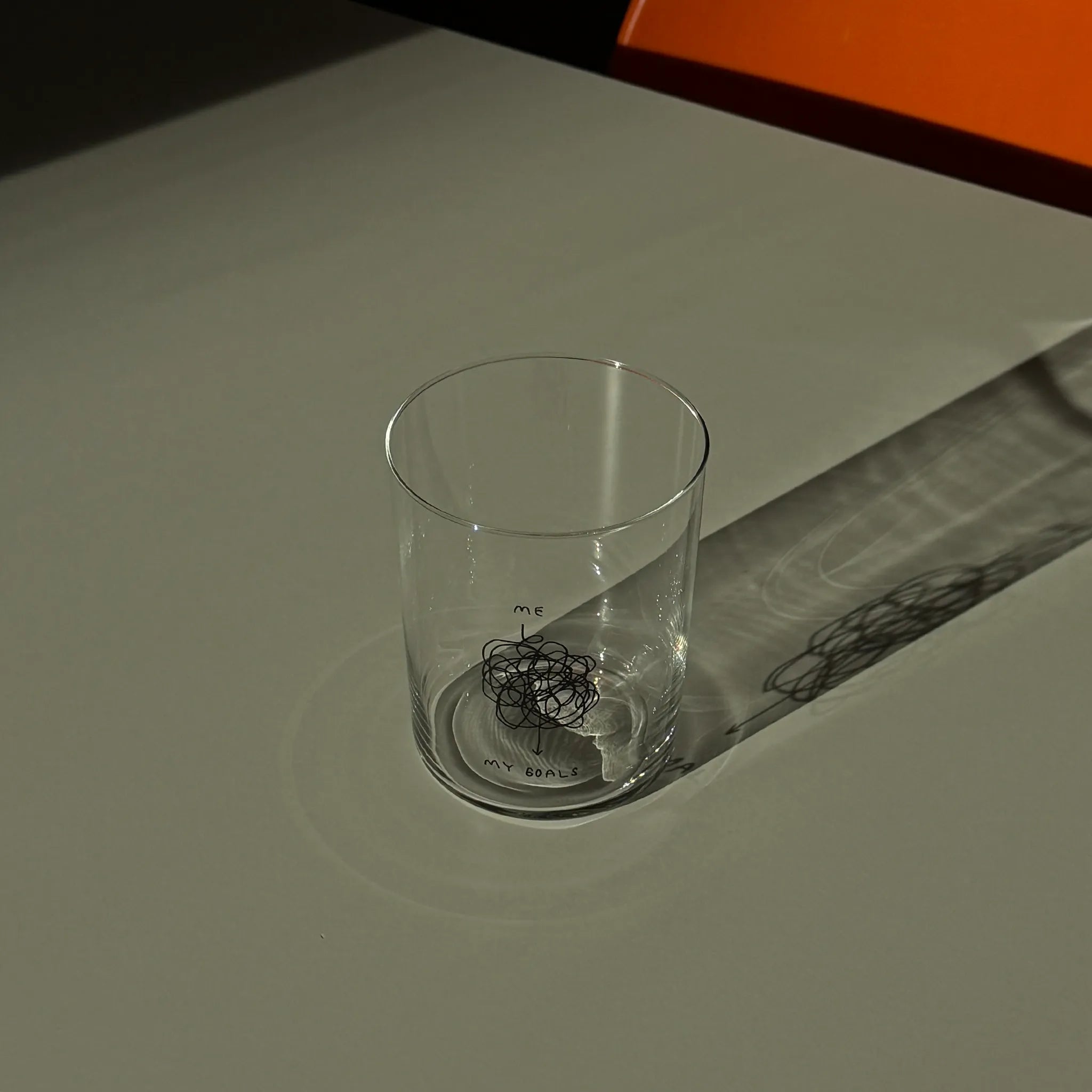 Großes 500ML Designer Glas „Me and My Goals“ mit sehr dünnen Glaswänden und minimalistischer schwarzer Illustration auf der Vorderseite, gestaltet von der Künstlerin und Illustratorin Johanna Schwarzer.

Das Motiv beschreibt den Weg "me" und "my goals" - verbunden werden die beiden Punktevon einer sehr langen wirren Linie die sehr viele Kurven und Kreise dreht.

Das Glas steht auf einer Metallplatte.