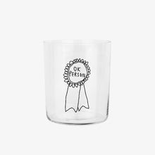 Großes Designer-Trinkglas mit sehr dünnen Glaswänden und einer schwarzen, einfarbigen Illustration auf der Vorderseite. Das Motiv zeigt eine Brosche inklusive einer Typografie in der geschrieben ist OK PERSON auf weißem Hintergrund.