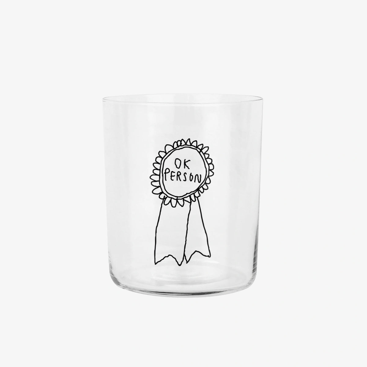 Großes Designer-Trinkglas mit sehr dünnen Glaswänden und einer schwarzen, einfarbigen Illustration auf der Vorderseite. Das Motiv zeigt eine Brosche inklusive einer Typografie in der geschrieben ist OK PERSON auf weißem Hintergrund.