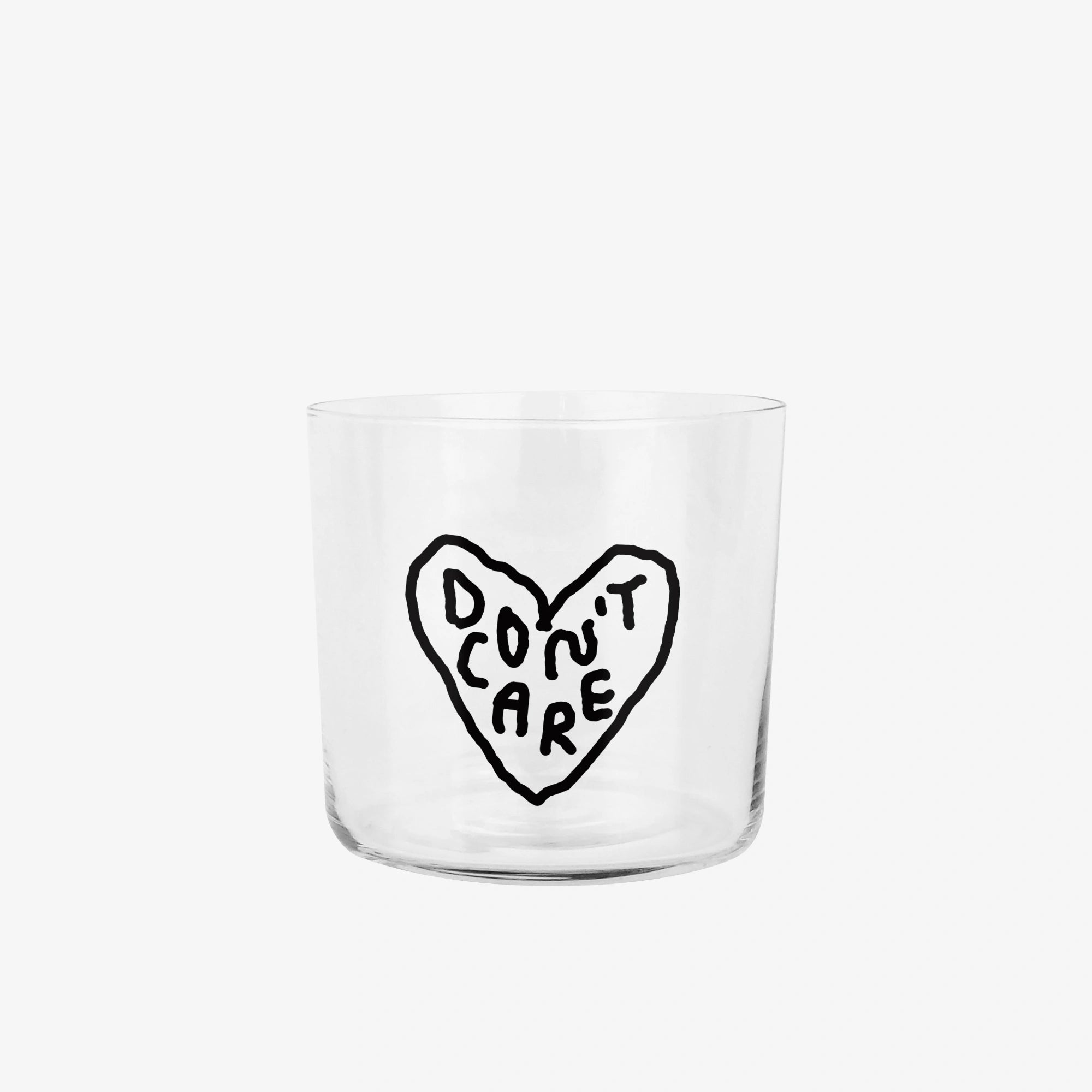 Transparentes Medium Designer Glas mit schwarzem Schriftzug "DON'T CARE" in einem Herz mit dünnen Wänden und Boden. Das Glas steht vor weißem Hintergrund.
