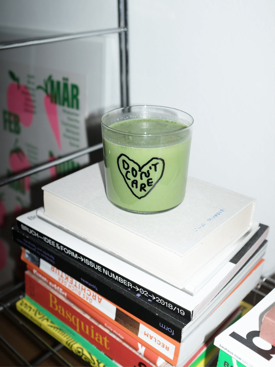 Wasserglas mit dem Schriftzug Dont Care. Um die Wörter ist ein Herz gemalt.  Das Glas steht auf mehreren Büchern und ist befüllt.